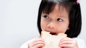 Bambina che mangia una fetta biscottata